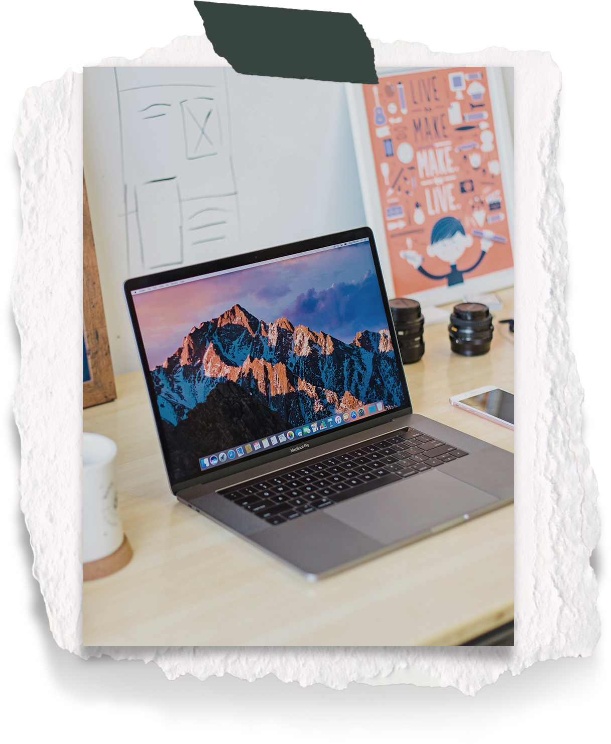 Laptop on desk with camera lenses in background